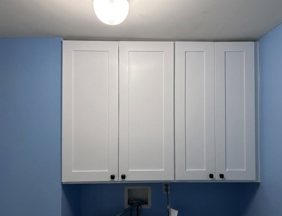 Wall-mounted shaker cabinets above a utility counter with closed storage