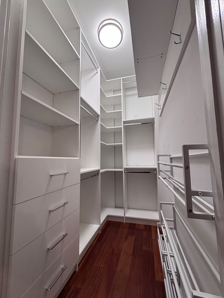 Narrow walk-in closet with a drawer bank and double hanging on both walls
