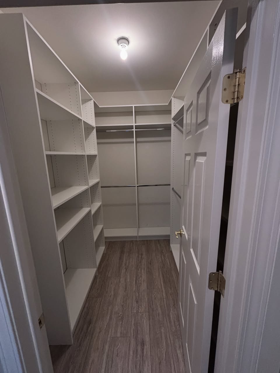 Narrow walk-in closet fitted with shelving and full-length hanging