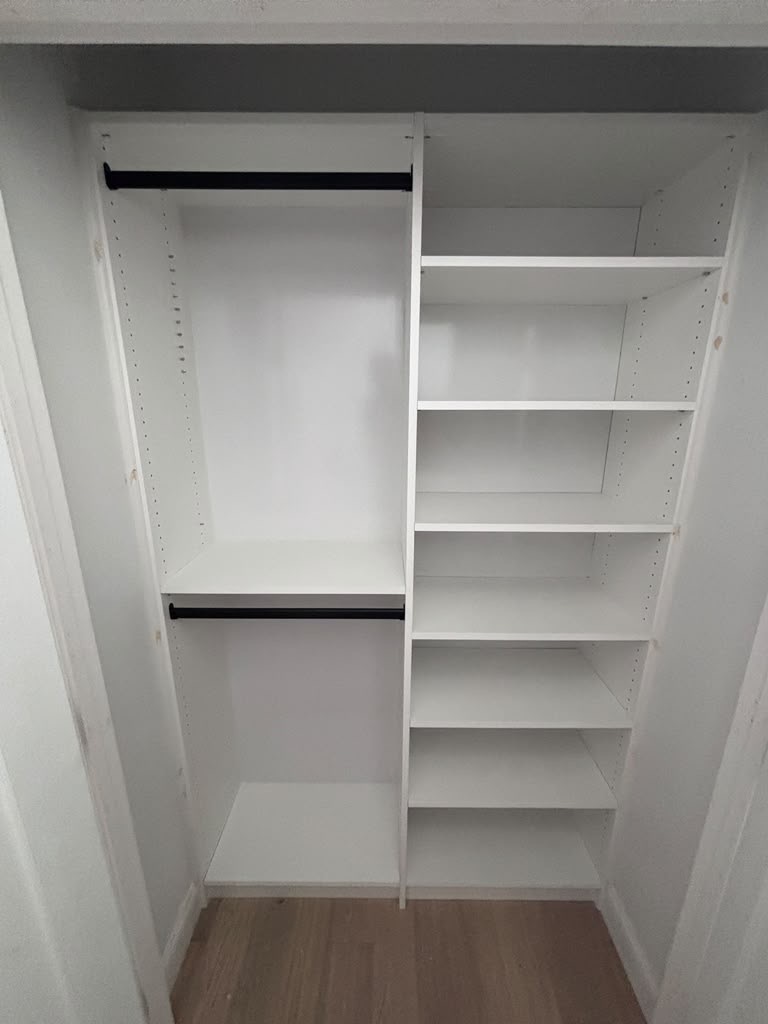 White reach-in closet fitted with double hanging and a run of adjustable shelves
